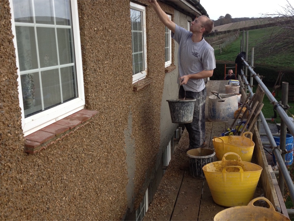Pebble dash render being applied to a residential property in Bletsoe with scaffolding around the exterior.