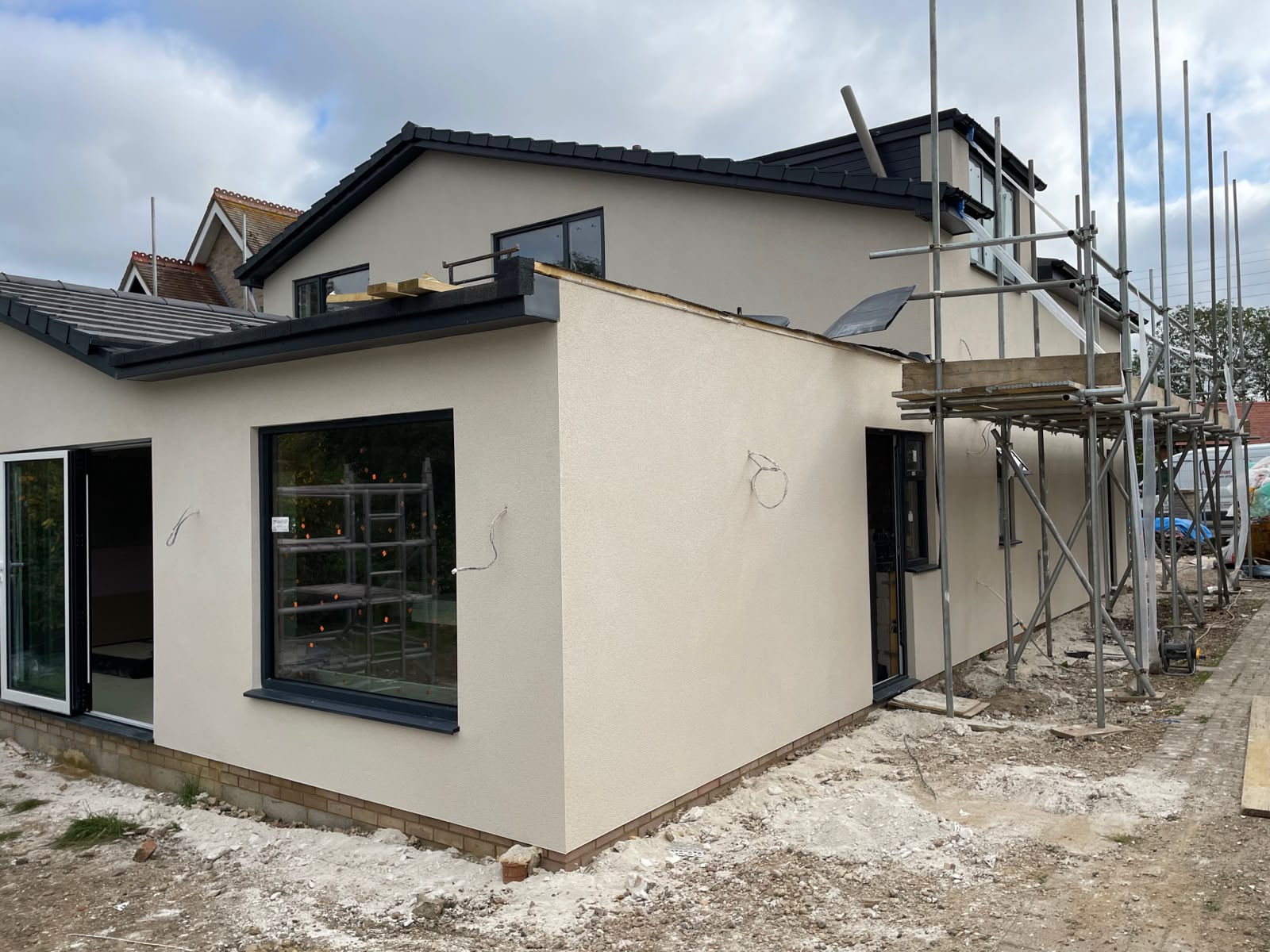 Parex monocouche render project in Felmersham on a residential property with cream render, dark windows and scaffolding around the exterior.